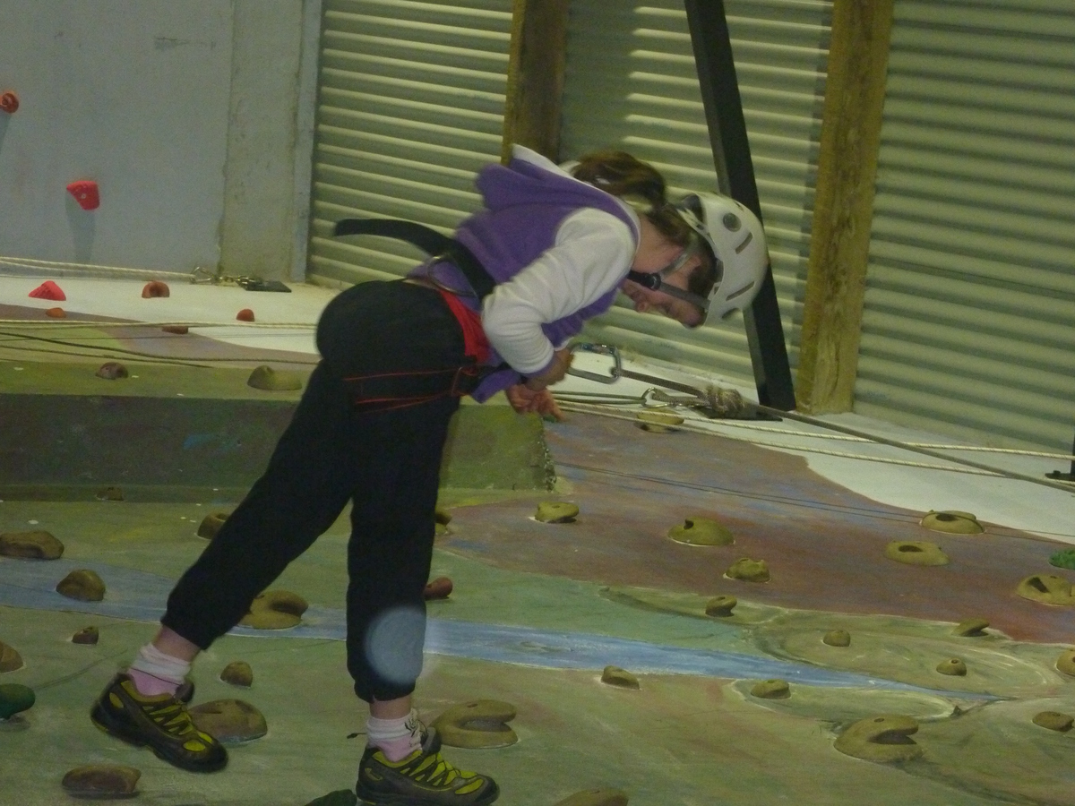 Olivia abseils down the climbing wall after speeding to the top