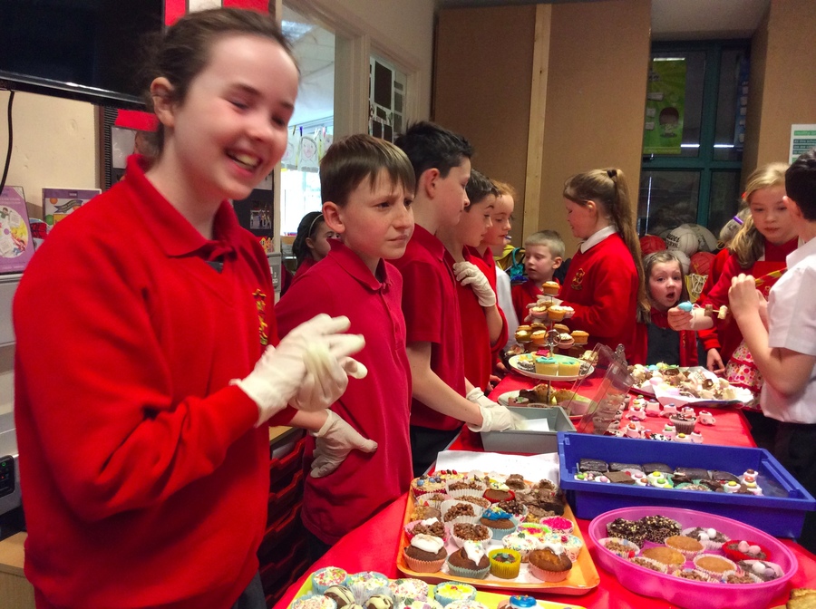 Selling buns in P.1/2, Eleanor has a fit of the giggles whilst Harry is very serious looking!