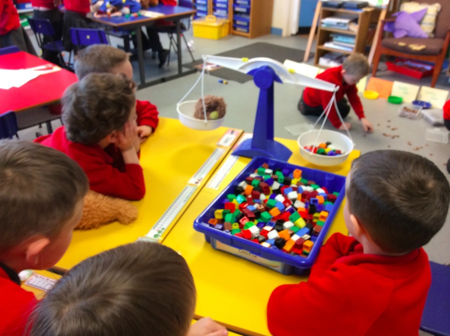 Some children in P.2W are estimating and weighing a teddy