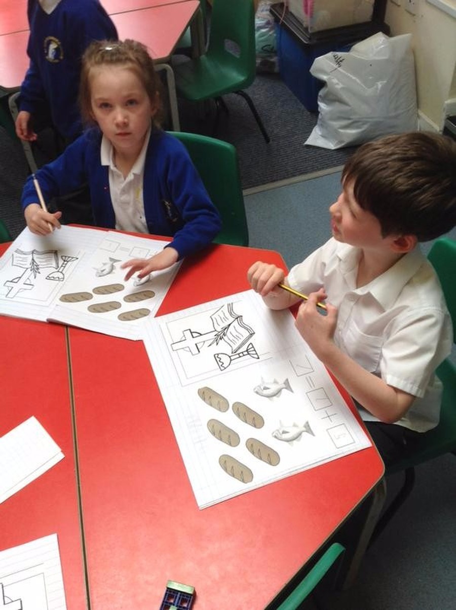 Children in Reception writing the sentence 'He is Risen' during their RE lesson.