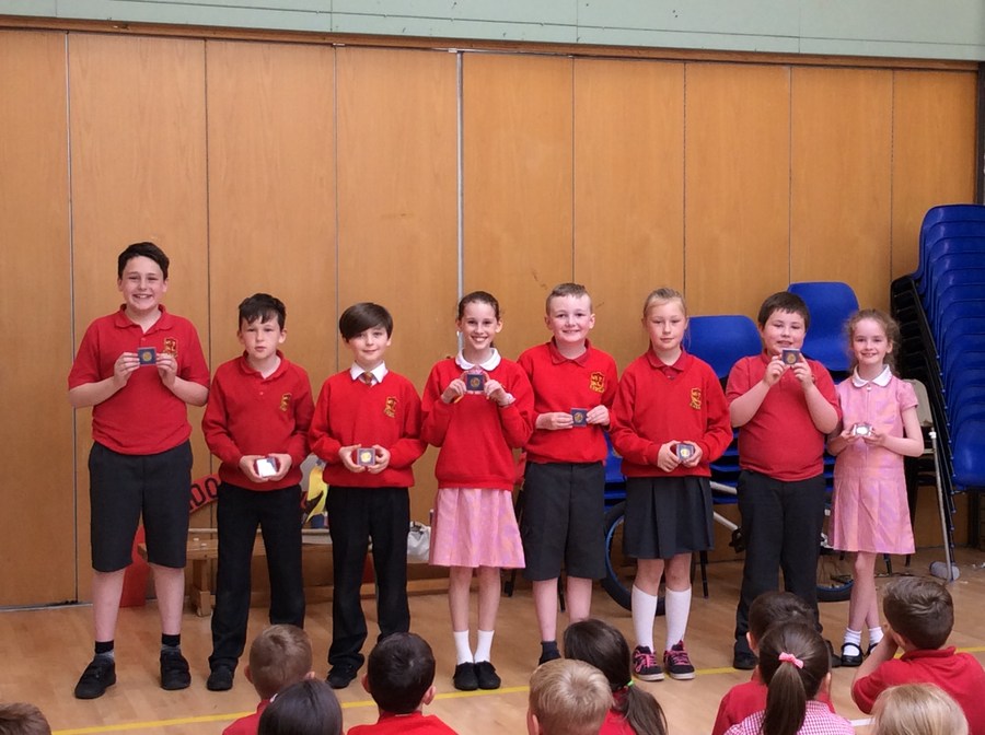 Children from P.4-P.7 who won celebration coins for the Queen's 90th birthday.